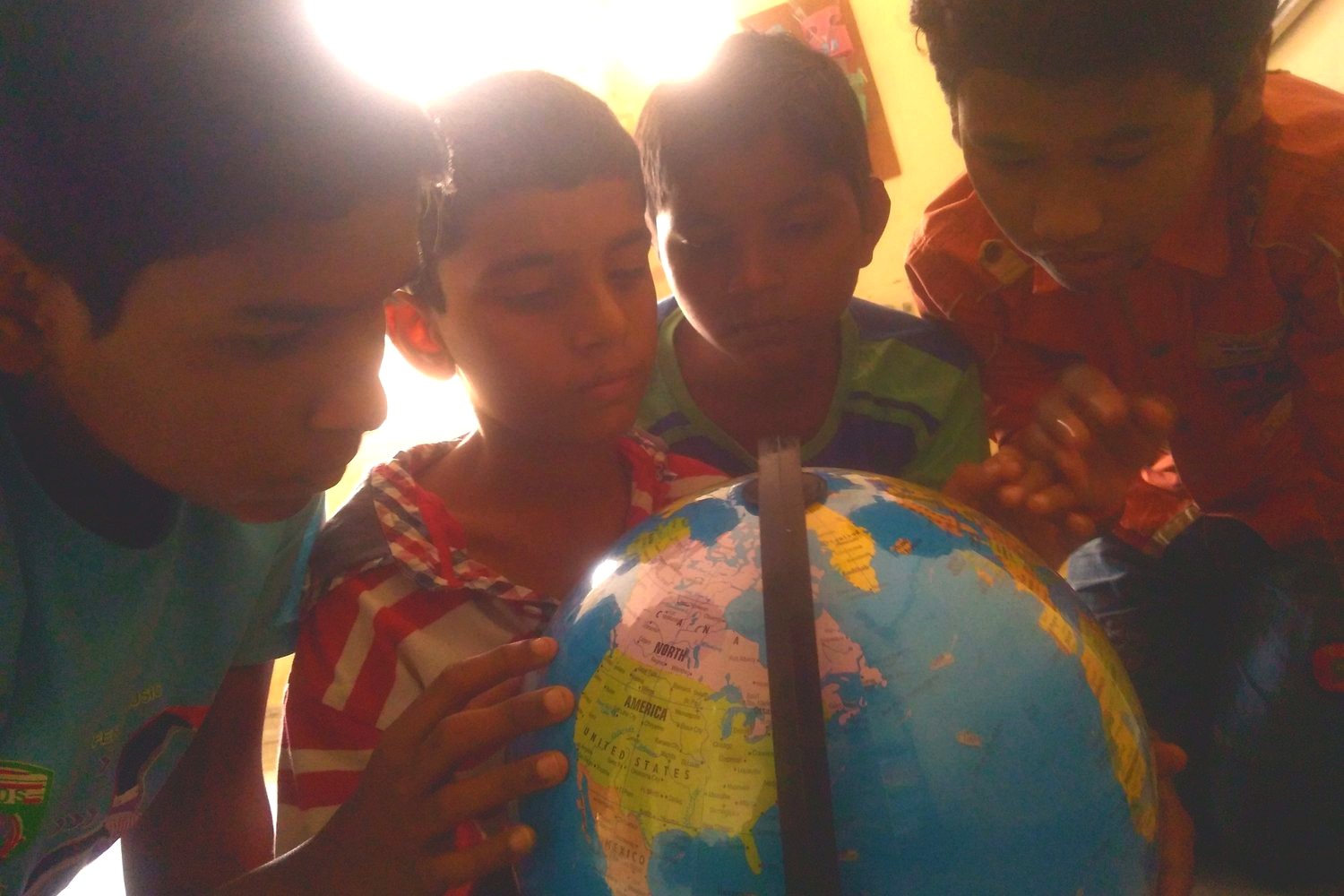 Children exploring a map of the world at Touching Lives